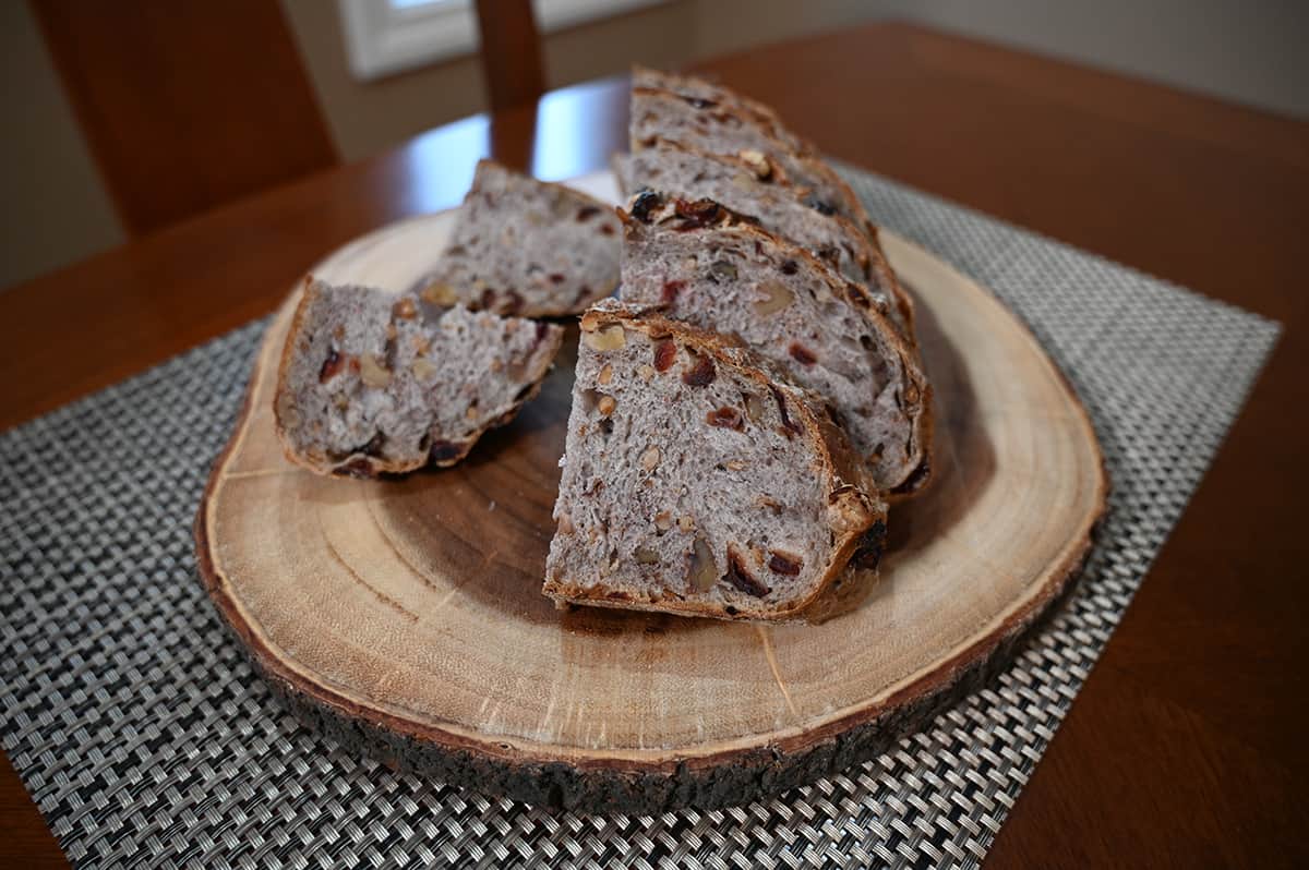 Side view image of the cranberry walnut bread sliced and sitting on a cutting board so you can see the inside of the bread.