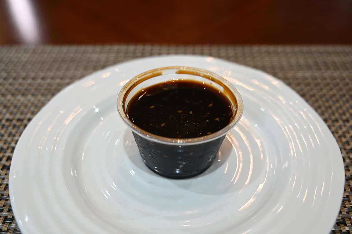 Side view image of one of the containers of soy sauce that comes in the container of yakisoba sitting on a plate.