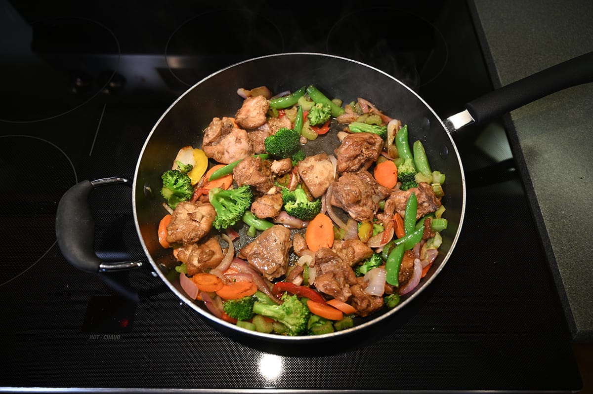 Top down image of the vegetables and chicken from the yakisoba being cooked in a frying pan on the stovetop.