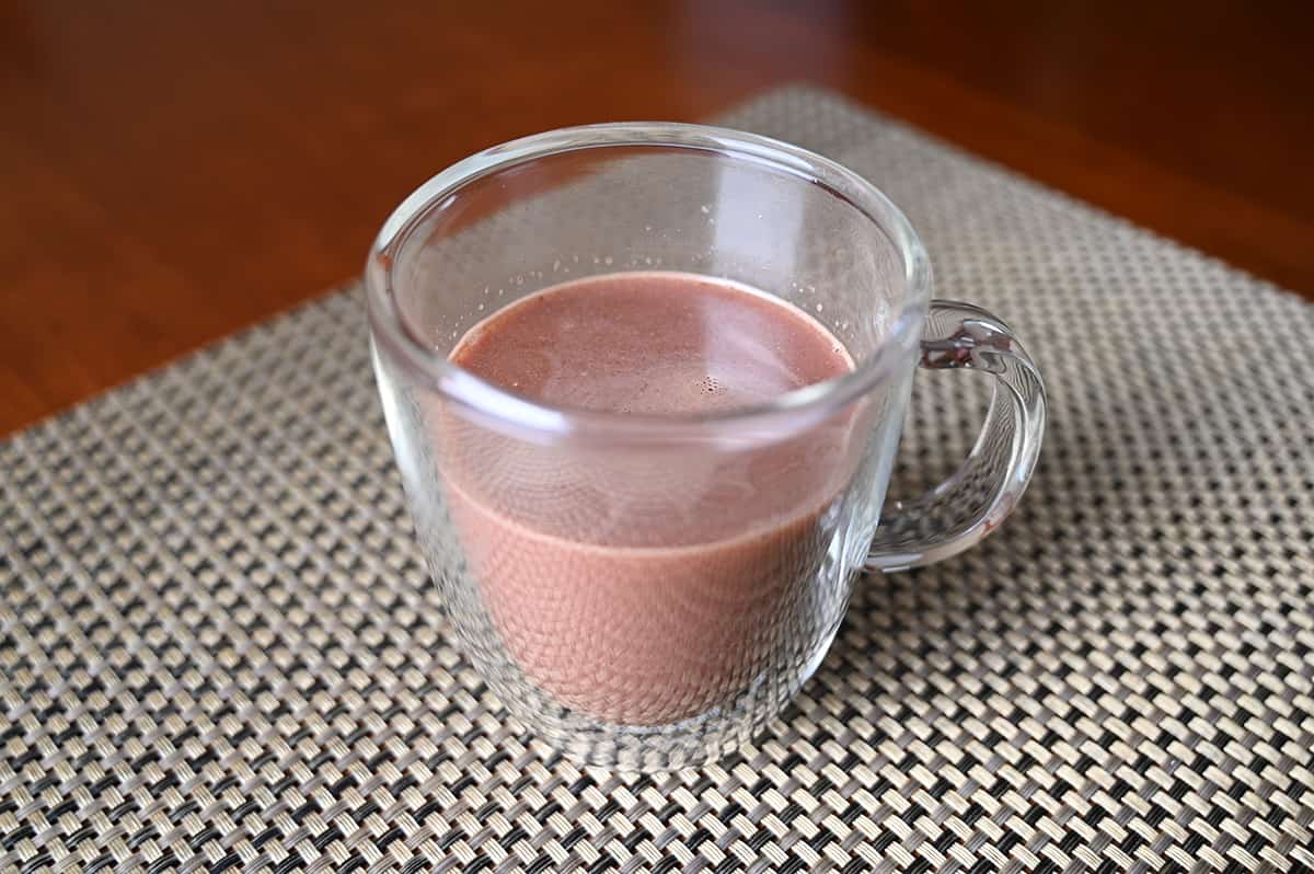 Image of a clear mug filled with candycane hot cocoa sitting on a table.