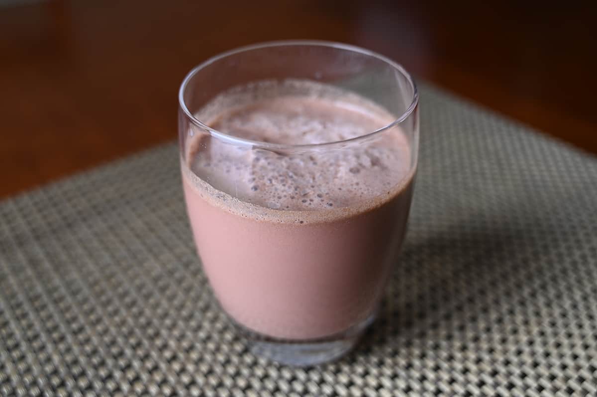 Image of a frozen candycane cocoa in a clear glass sitting on a table.