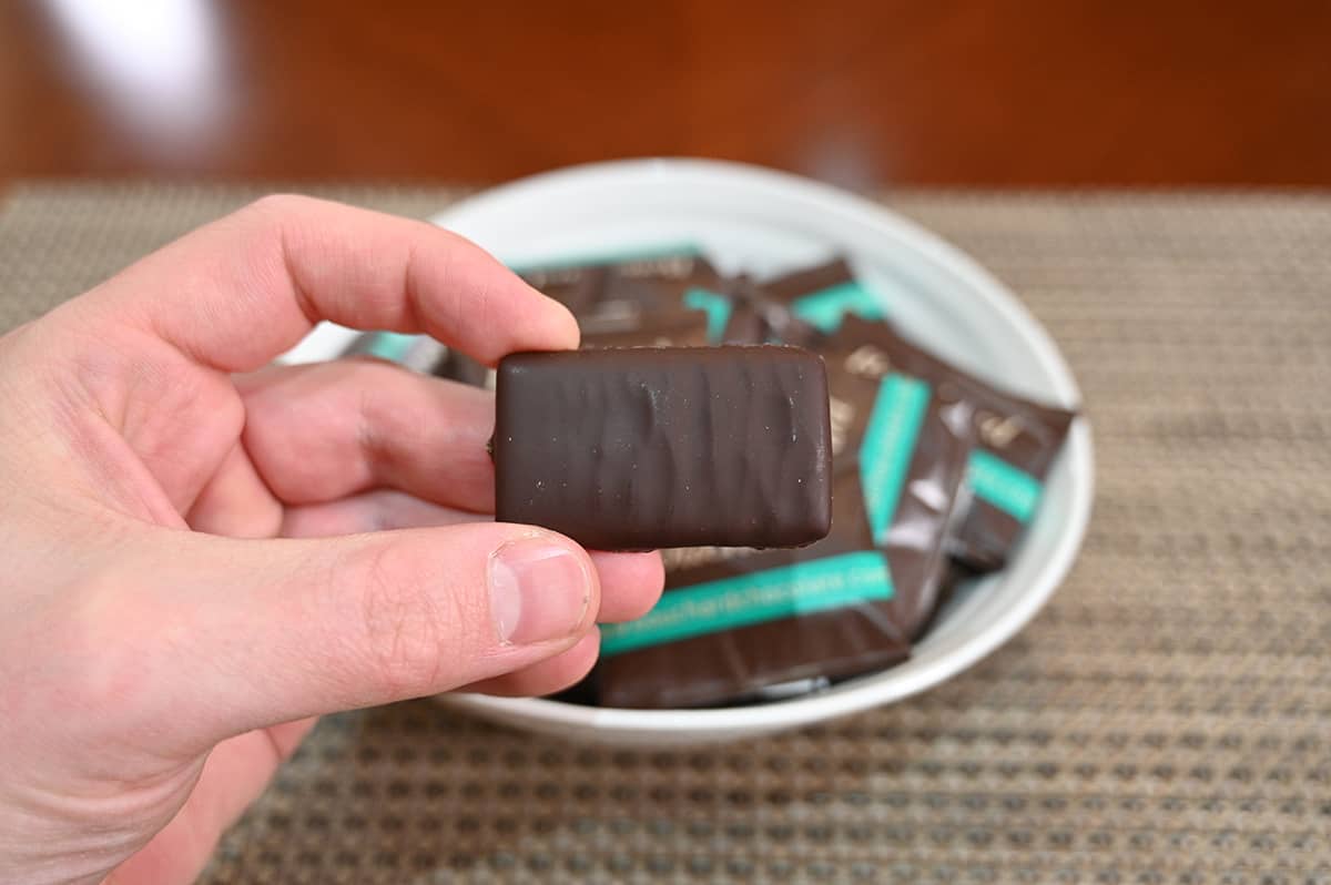 Closeup image of a hand holding one chocolate unwrapped close to the camera.