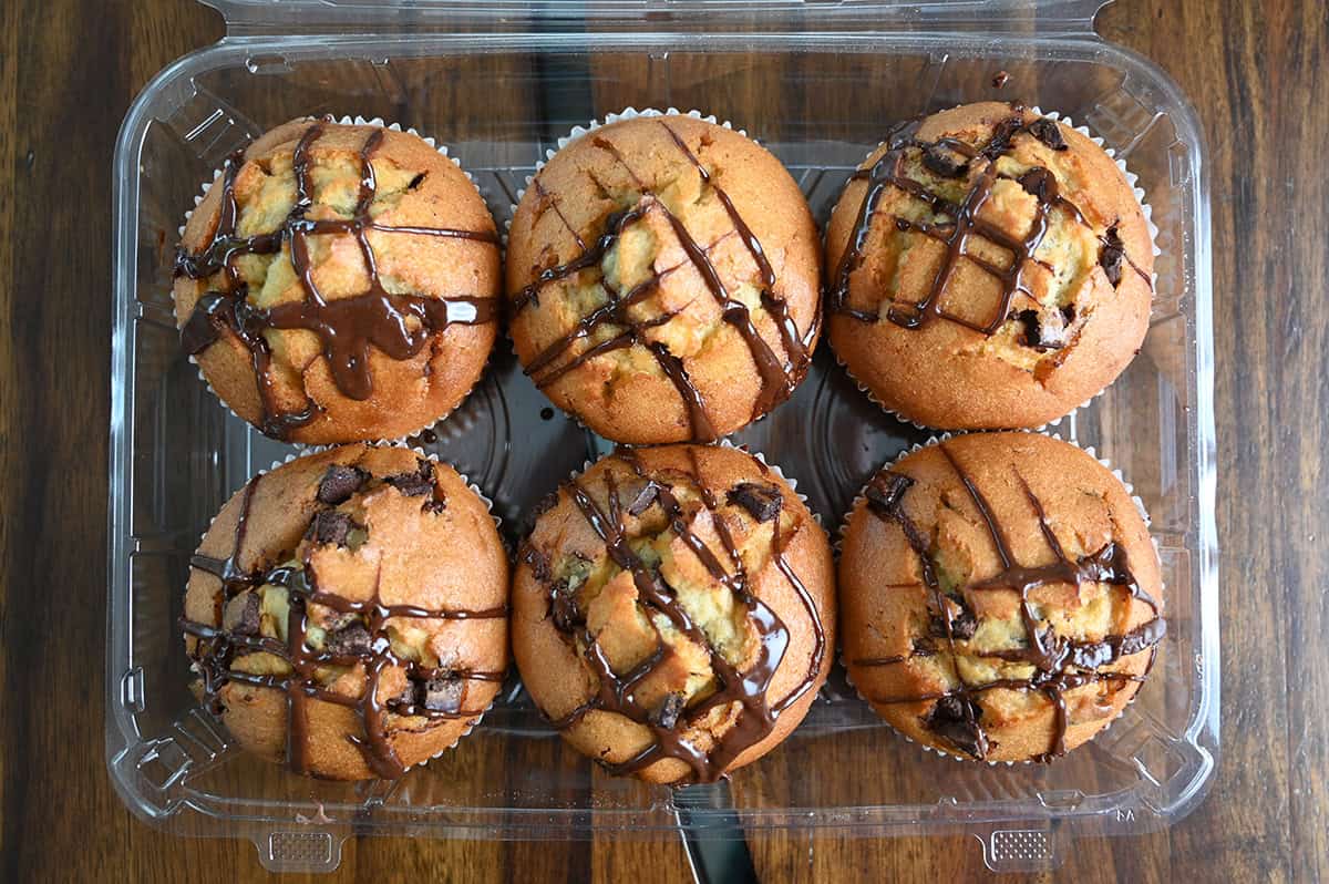 Top down image of an open container of six vanilla chocolate chunk muffins.