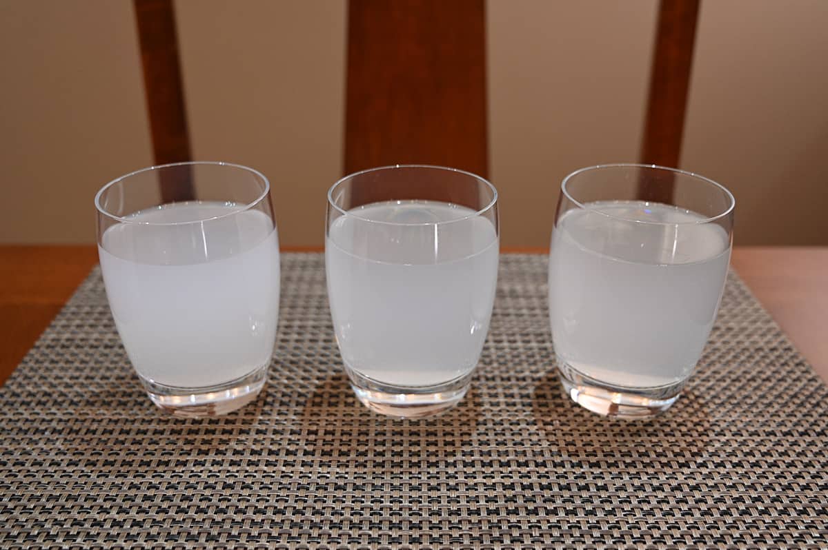 Image of three clear glasses sitting on a table, each glass has energy drink poured into it. There is breezeberry, cherry slush and cosmic dust served.