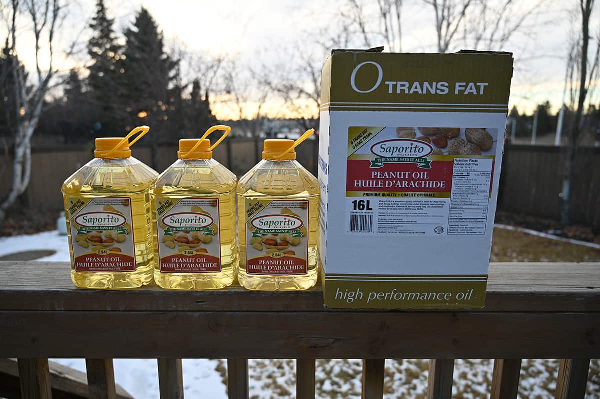 Image of three large full containers of peanut oil sitting on a deck outside beside a box for the peanut oil.