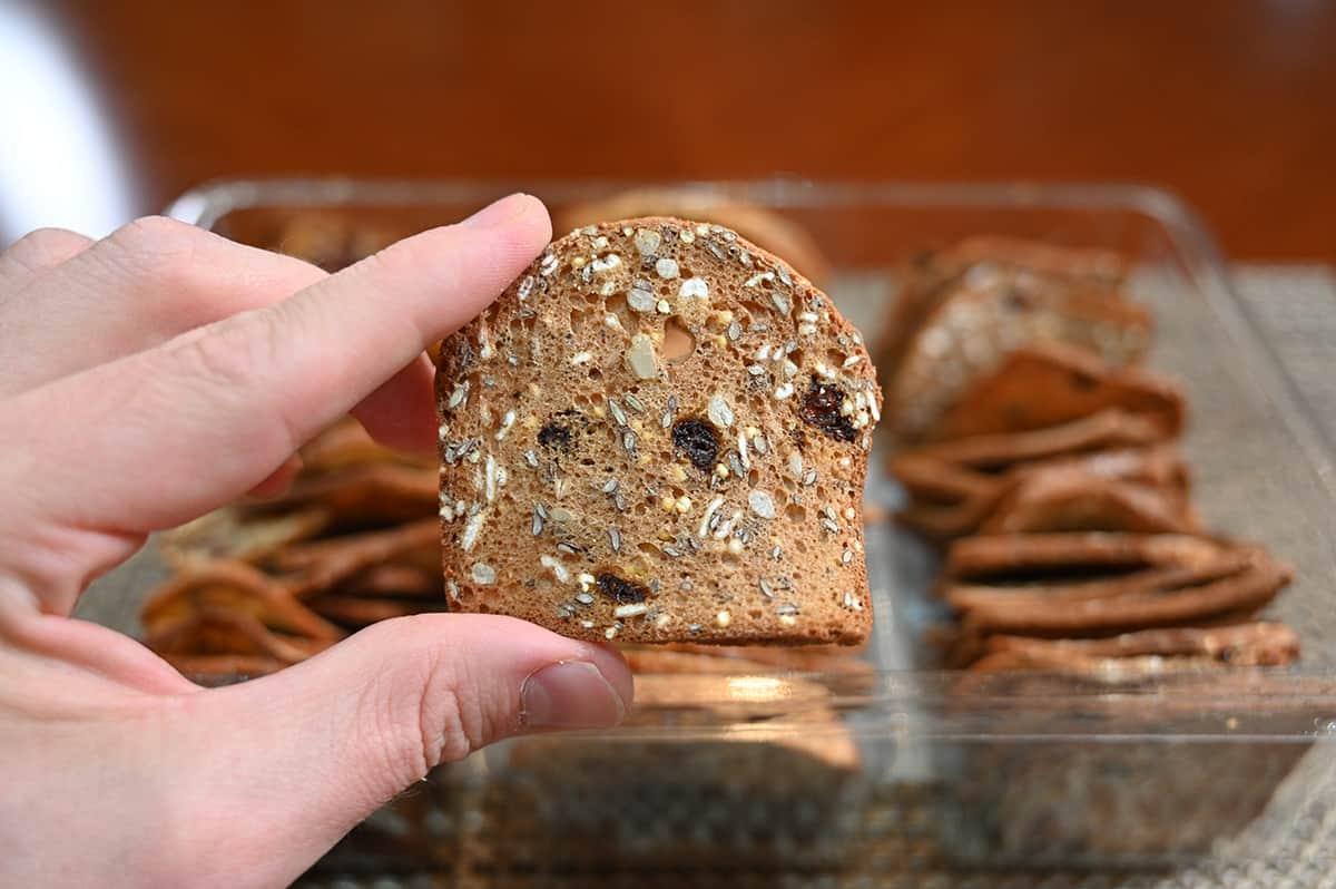 Image of a hand holding a fig, vanilla and black pepper cracker close to the camera.