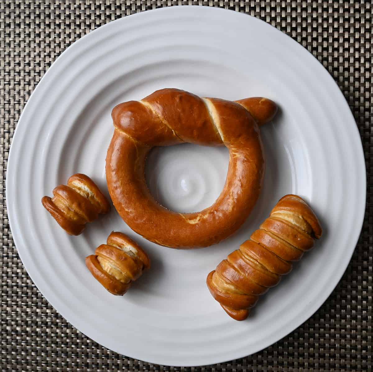 Top down image of one wheelhouse pretzel, one turnbuckle stick pretzel and two one-timer bite pretzels served on a white plate.