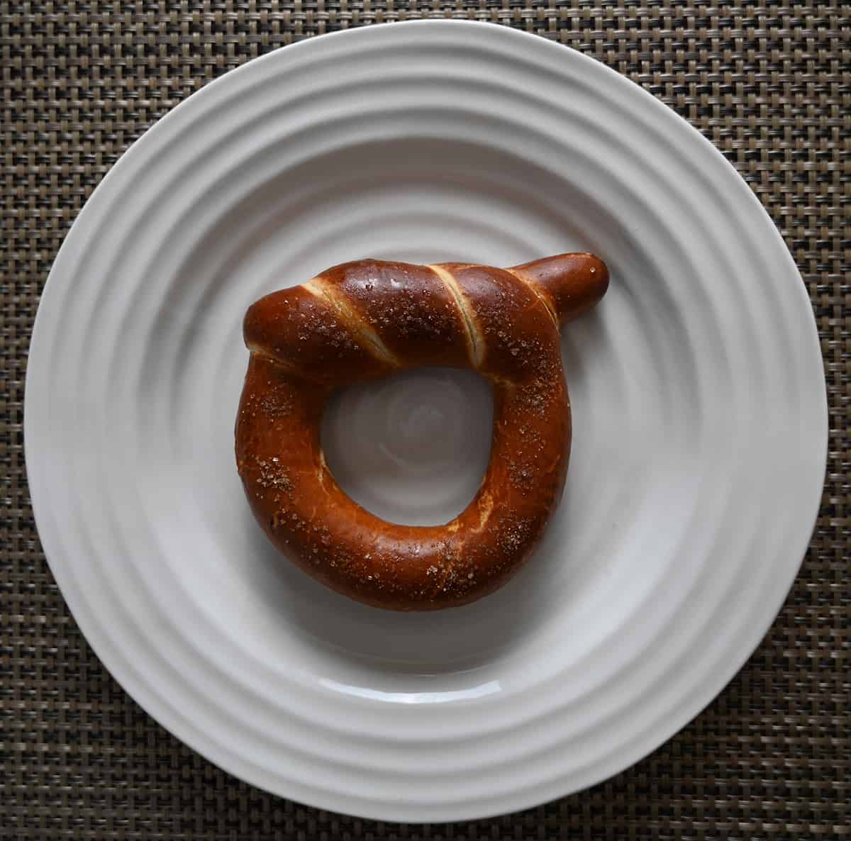 Top down image of one baked wheelhouse pretzel served on a white plate.
