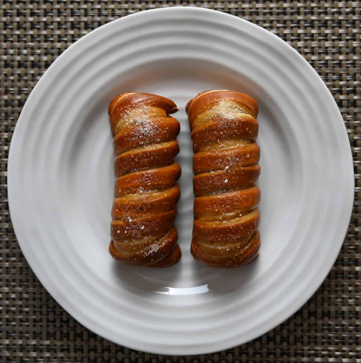 Top down image of two turnbuckle stick pretzels baked and served on a white plate.