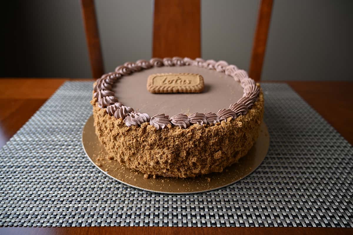 Side view image of the cake sitting on a table showing the side of the cake covered in cookie crumbs.