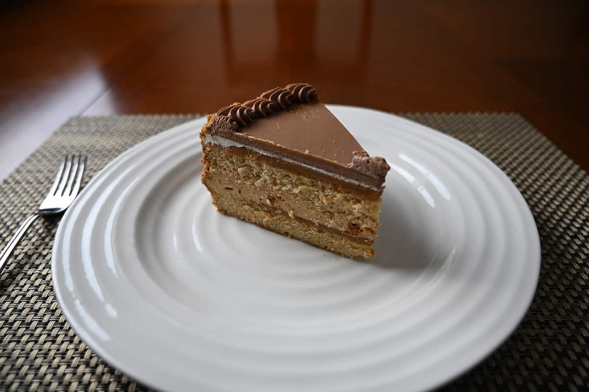 Side view top down image of one piece of biscoff cake served on a white plate showing the top and middle layers together.