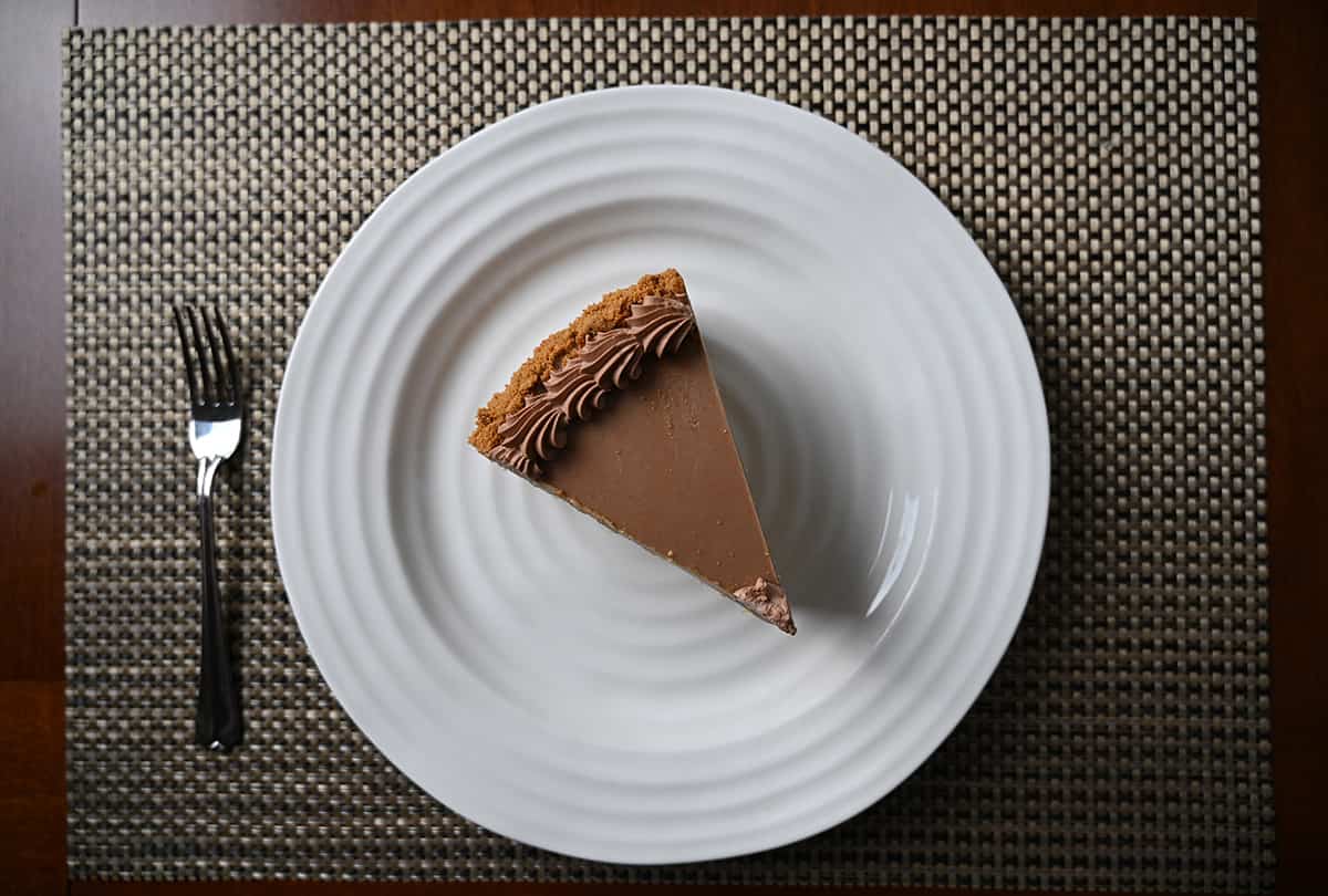 Top down image of one piece of cake served on a white plate with a fork beside the plate.