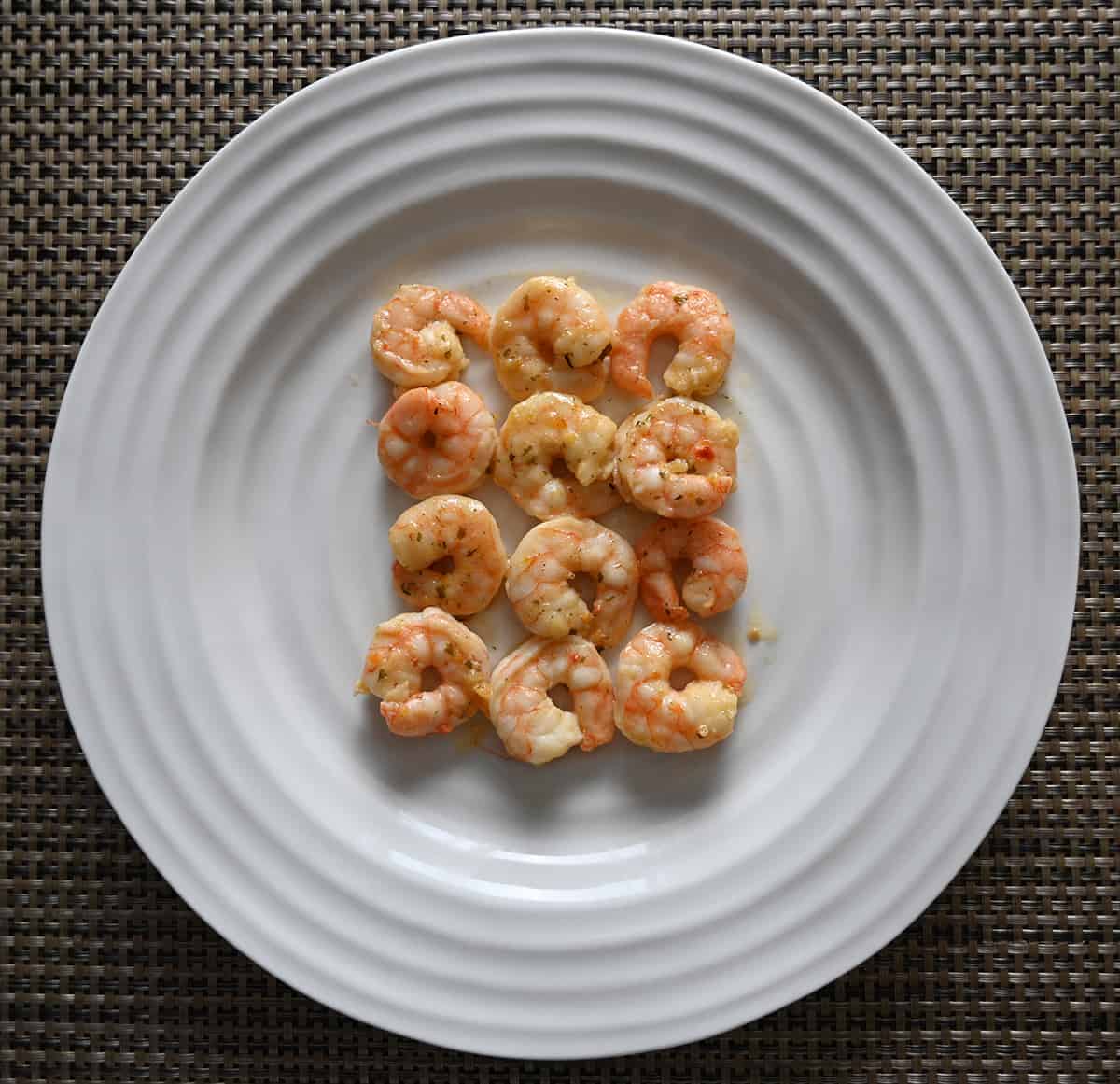 Top down image of 12 garlic butter shrimp served on a white plate.