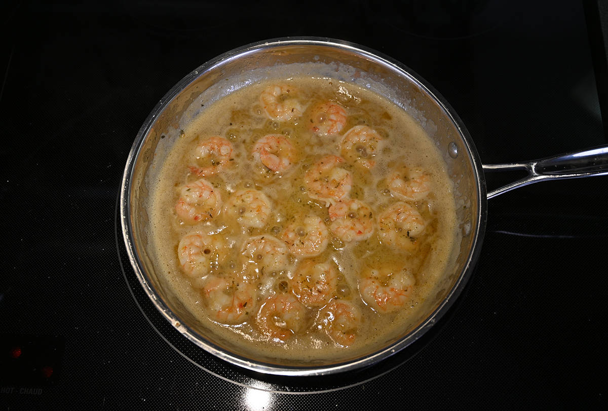 Top down image of the garlic butter shrimp sitting in a pan after being sauteed. They're in a pool of garlic butter.