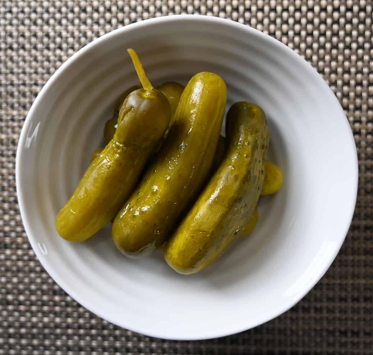 Top down image of a bowl of baby dill pickles.