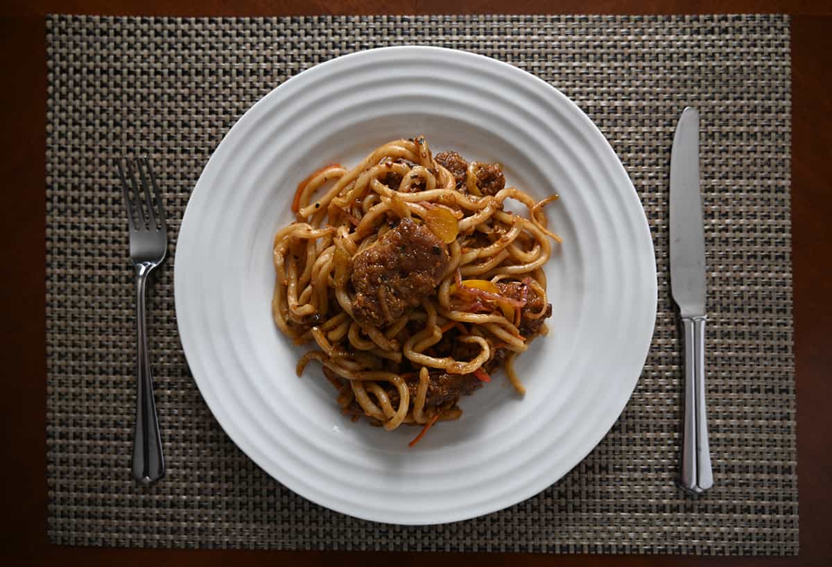 Top down image of a plate of ginger stir fry with a fork and knife beside it.