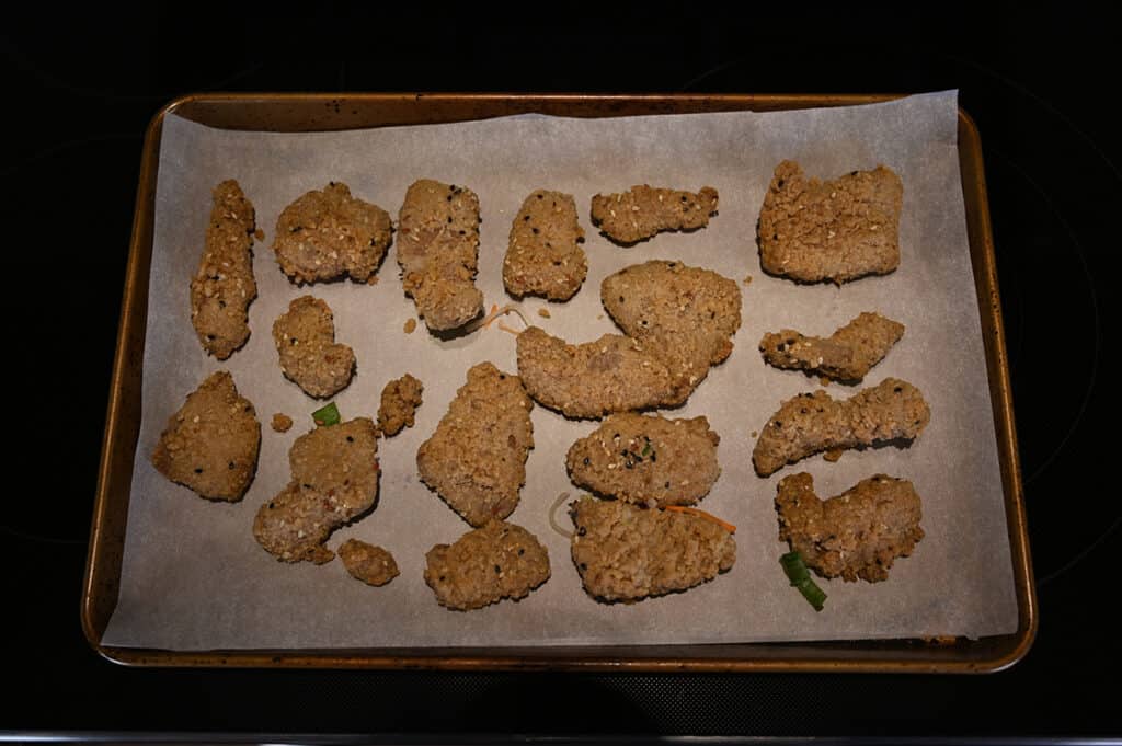 Top down image of a parchment lined cookie sheet with uncooked ginger beef on it, ready to go in the oven.