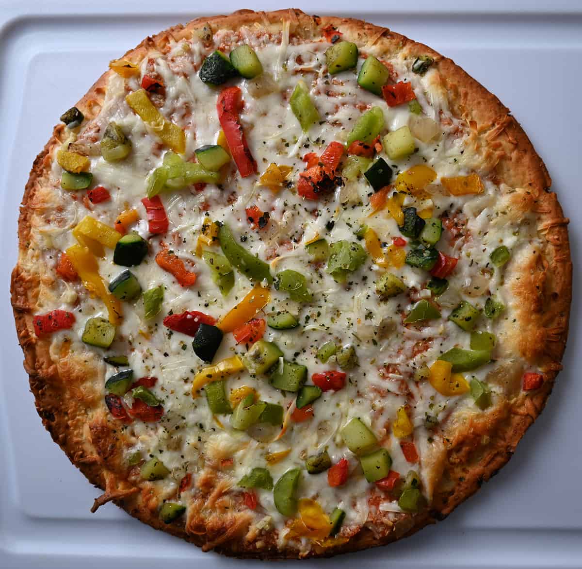 Top down image of an entire baked cauliflower pizza sitting on a cutting board.