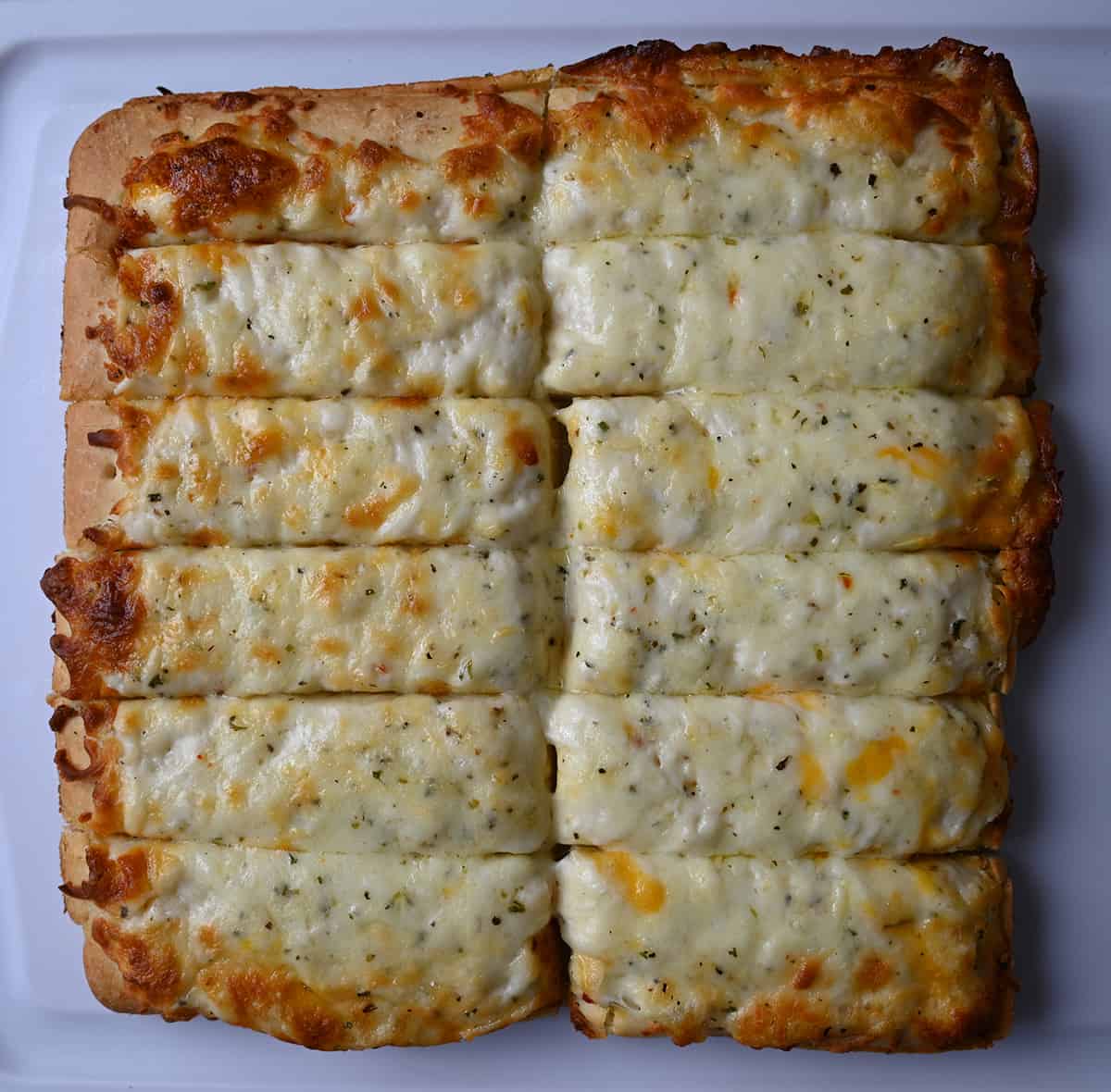 Closeup image of one cheese bread on a cutting board cut into 12 pieces.