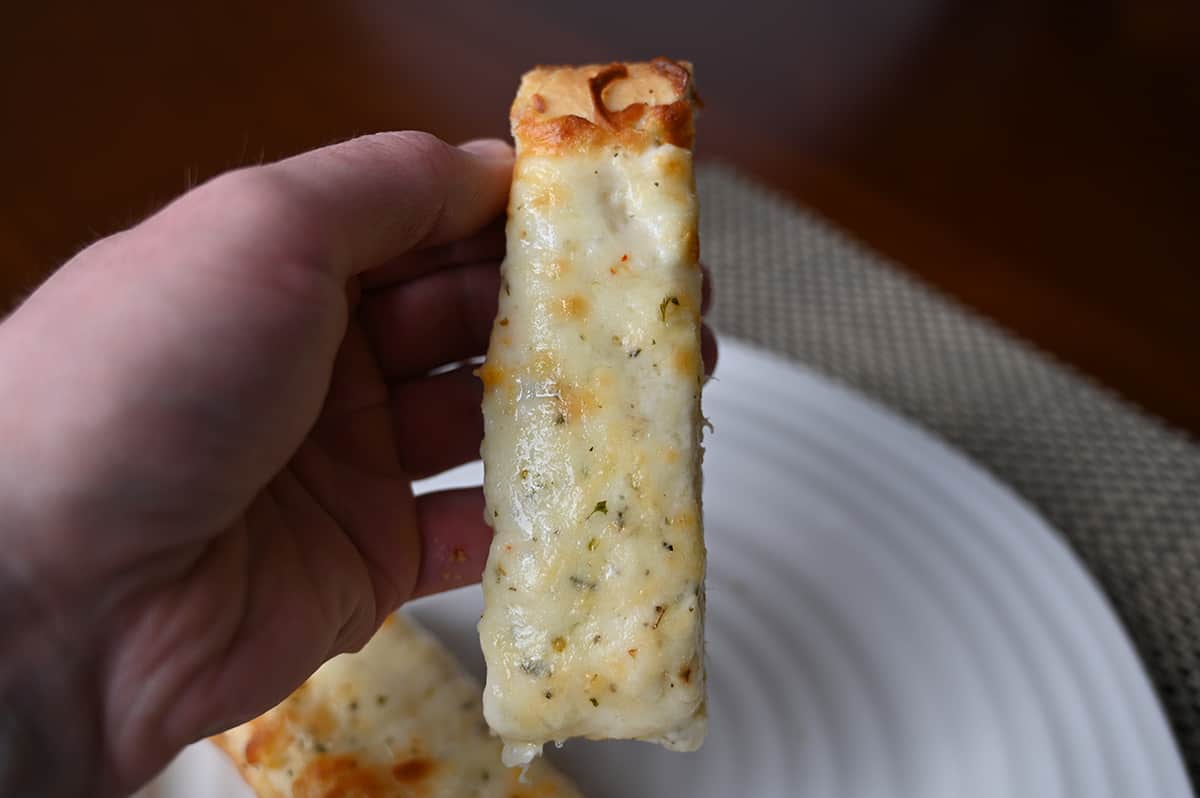 Closeup image of a hand holding one piece of cheese bread close to the camera. 