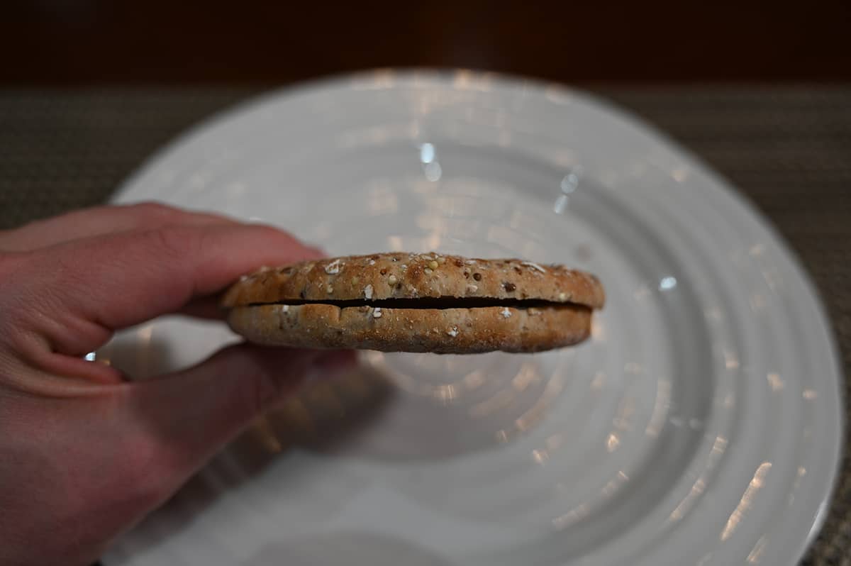 Closeup sideview image of a hand holding one sandwich thin close to the camera without any toppings in the middle.