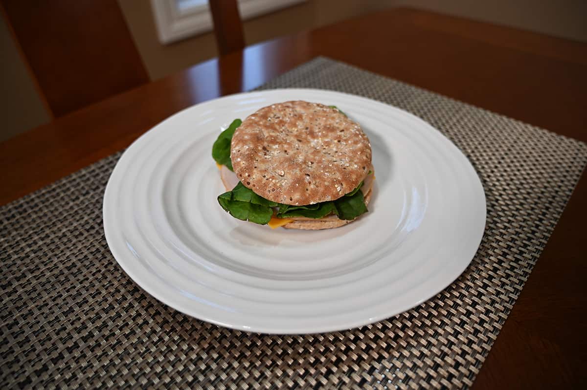 Side view image of a sandwich thin with turkey and lettuce in the middle served on a white plate.