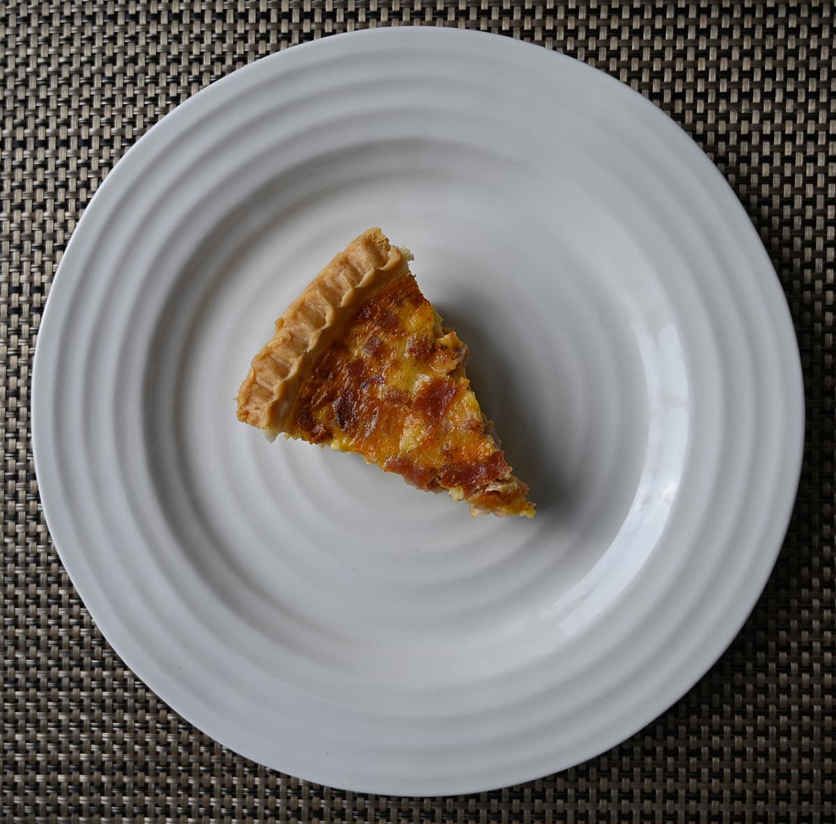 Top down image of one slice of quiche on a plate.