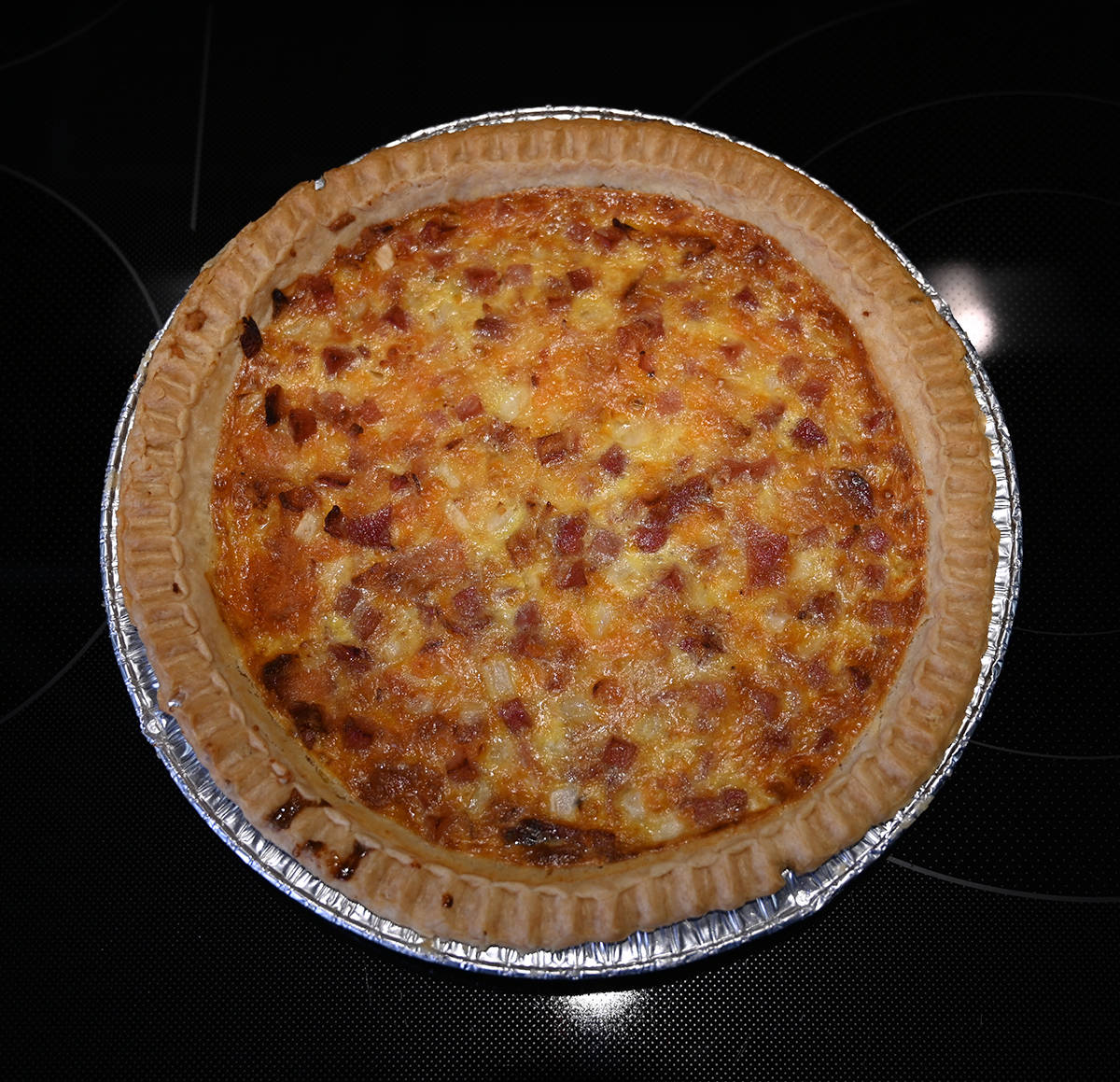 Top down image of the whole quiche out of the packaging sitting on a table after being baked.