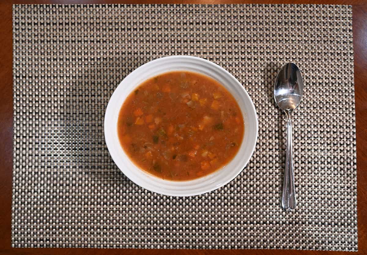Top down image of a bowl of soup sitting on a table with a spoon beside the soup.