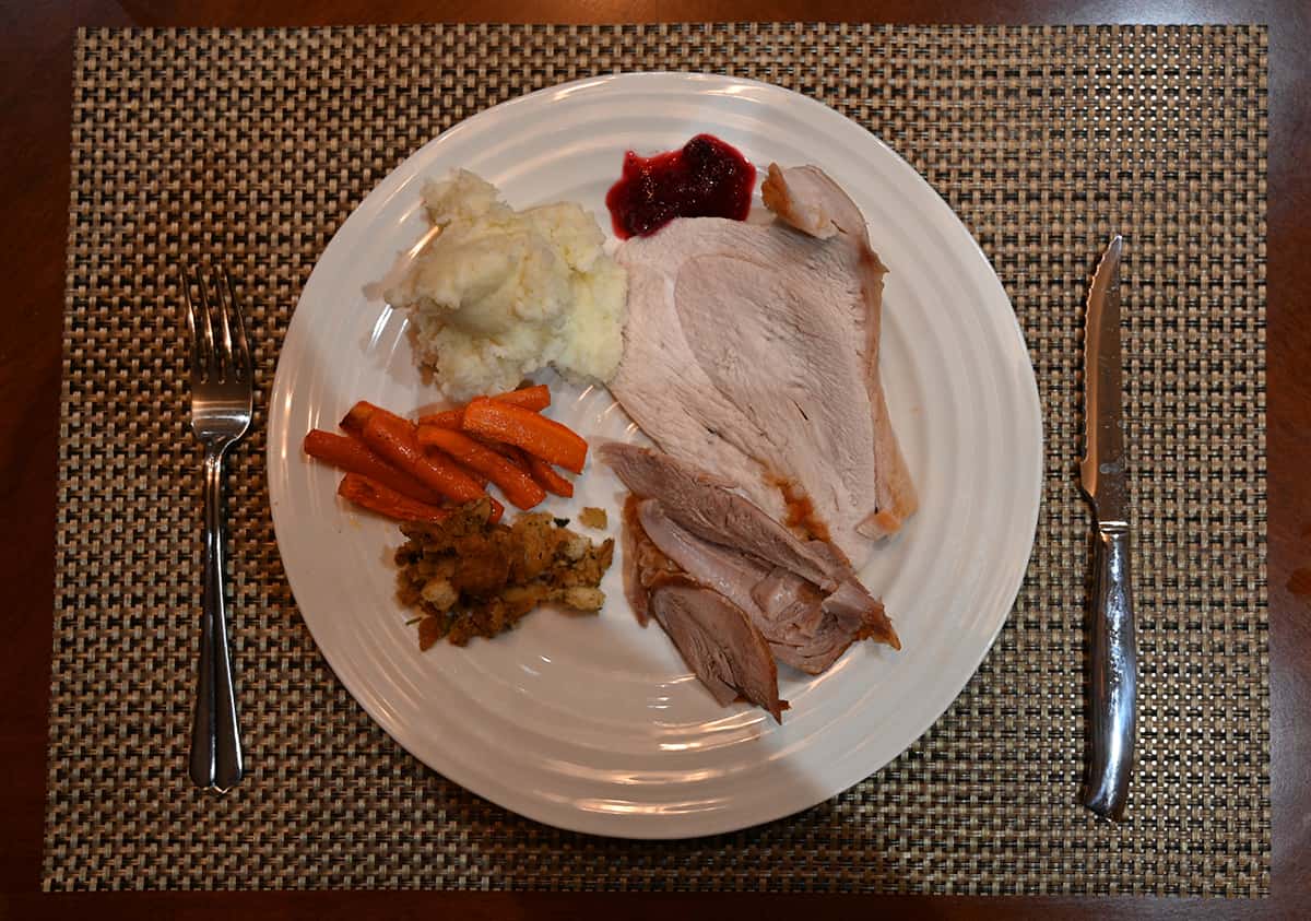Top down image of a plate of turkey, mashed potatoes, cranberry sauce, carrots and stuffing.