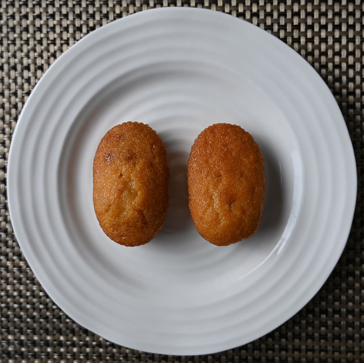 Top down image of two muffin bites unwrapped and served on a white plate.