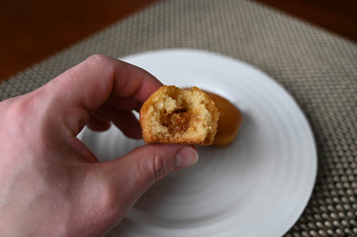 Closeup image of a hand holding one salted caramel muffin bite cut in half so you can see the caramel center.