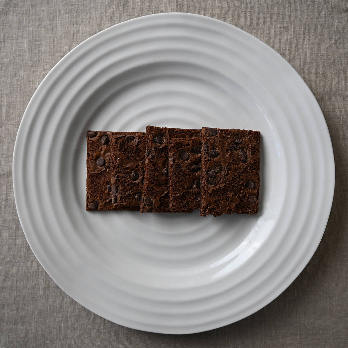 Image of five brownie brittle pieces served on a white plate.