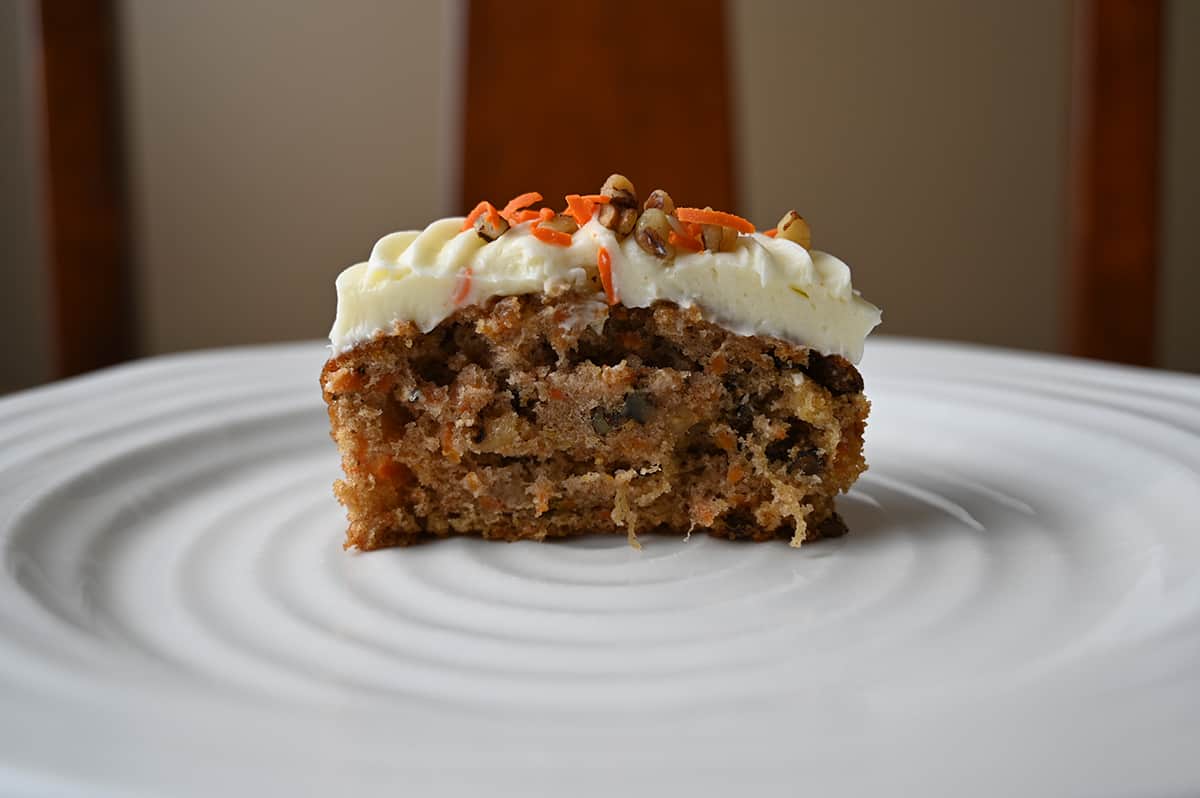 Sideview closeup image of one carrot mini cake cut in half so the center is visible. 