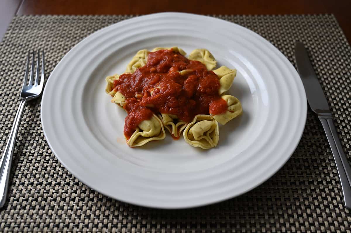 Sideview image of a plate of tortelloni with red sauce on it.