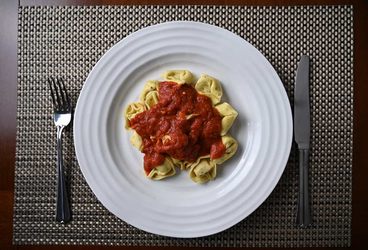 Top down image of a plate of tortelloni with red sauce on top.