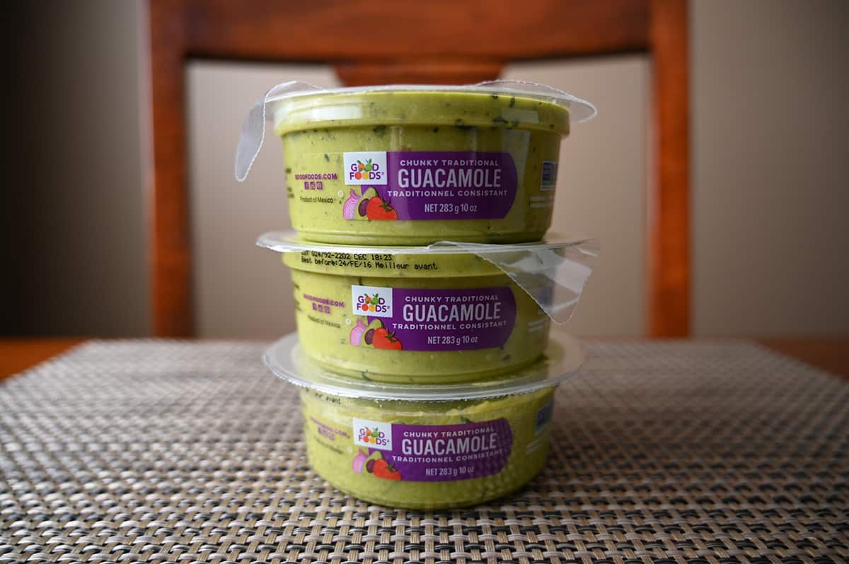 Side view image of three containers full of guacaole stacked on top of one another.
