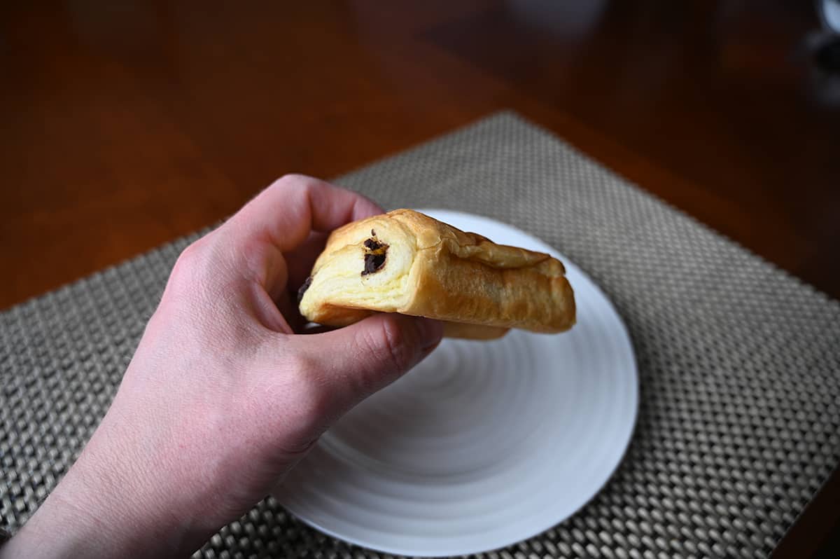 Image of a hand holding a chocolatine on its side close to the camera so you can see how thick it is.