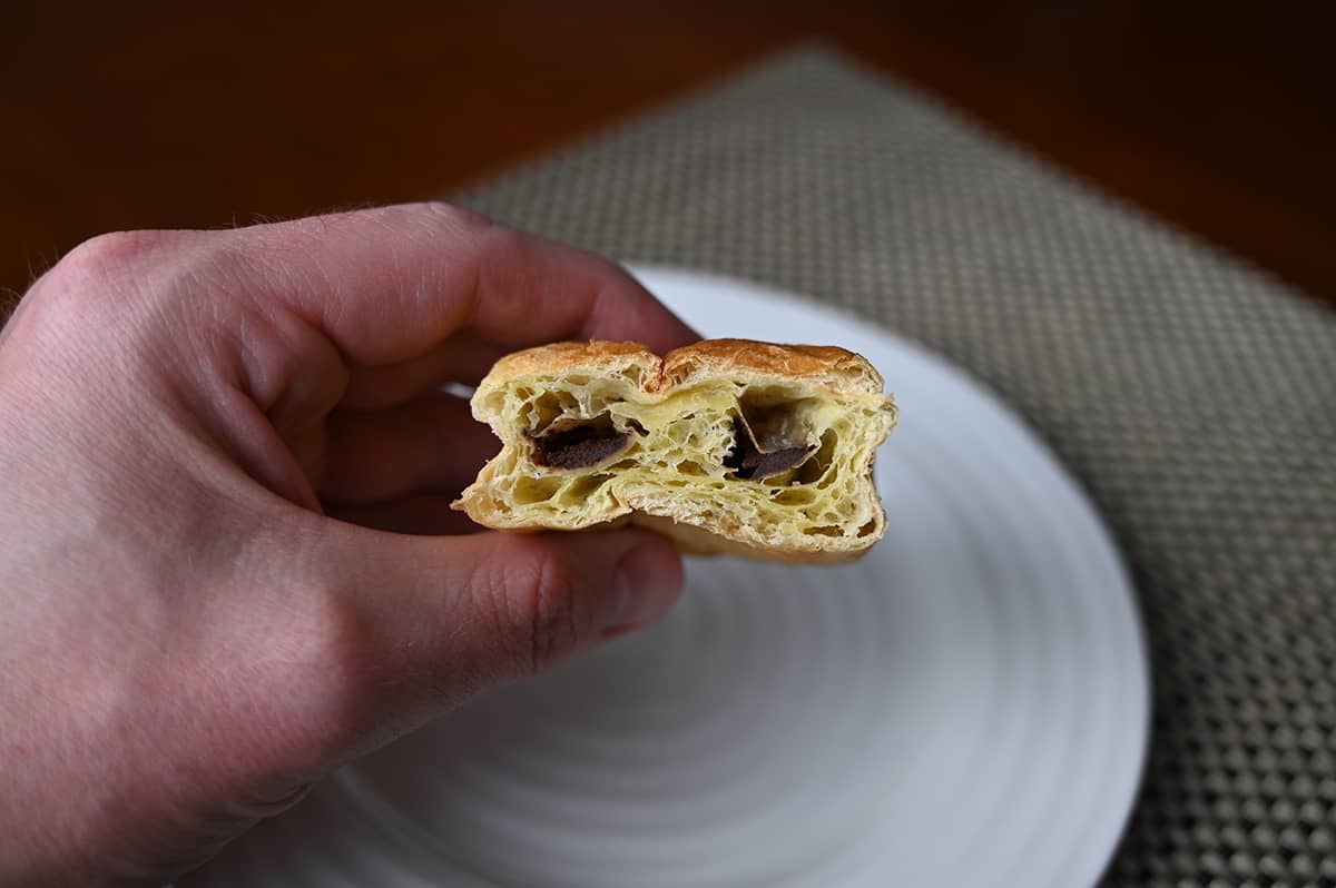 Image of a hand holding a chocolatine with a bite taken out of it so you can see the chocolate in the middle.