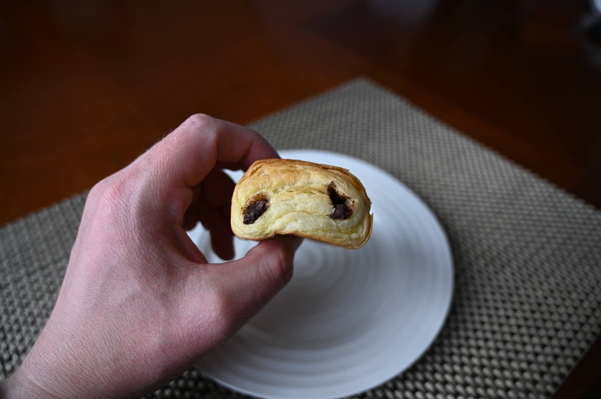 Image of a hand holding a chocolatine close to the camera so you can see the top of it.