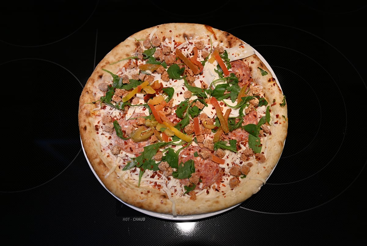 Top down image of one frozen pizza sitting on top of an oven ready to be baked.