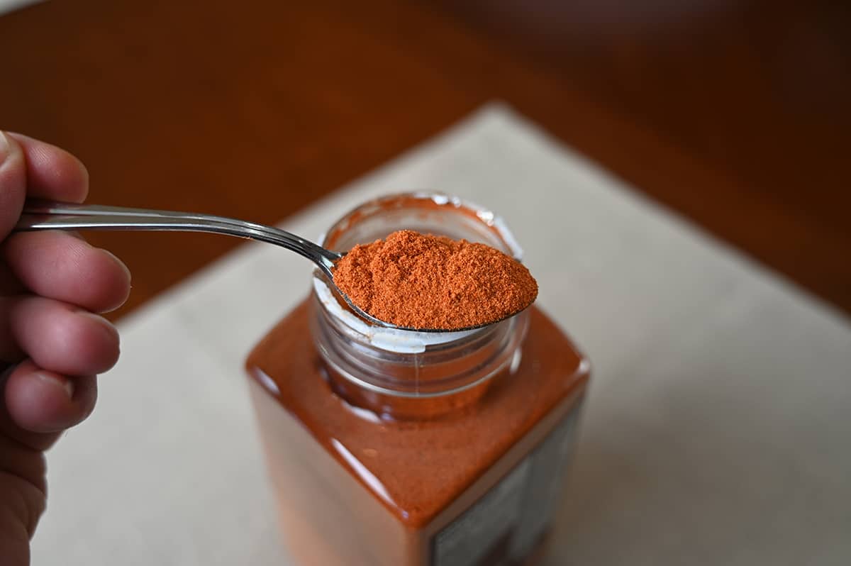Image of a spoonful of sriracha seasoning hovering over an open container of seasoning.