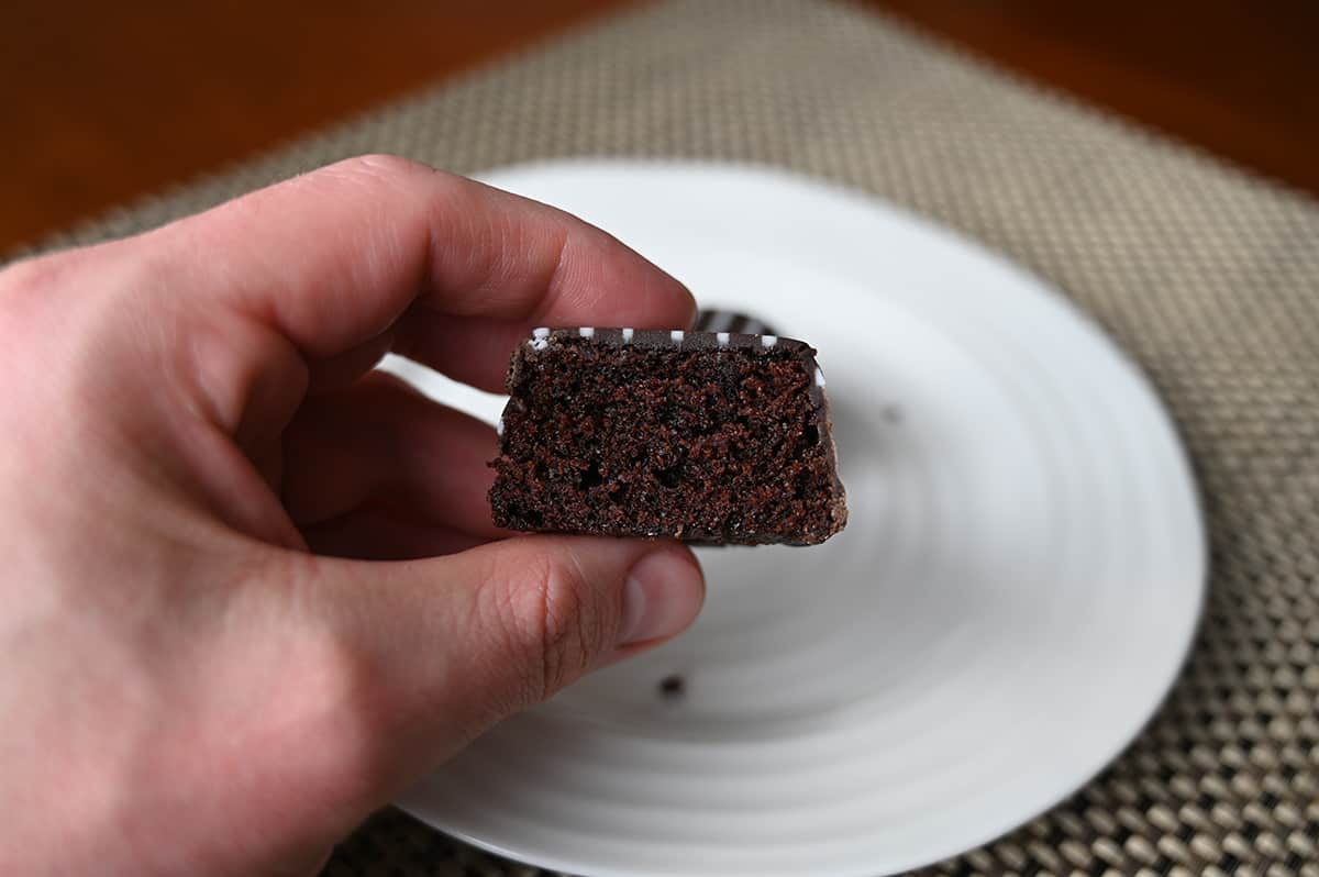 Sideview image of a hand holding one tuxedo bite with a bite taken out of it so you can see what the center looks like.