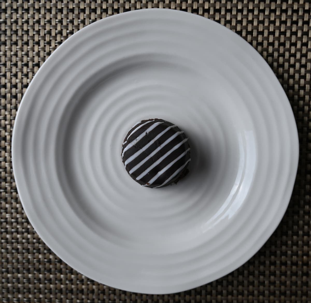 Top down image of one tuxedo cake bite served on a white plate so you can see the icing on top.
