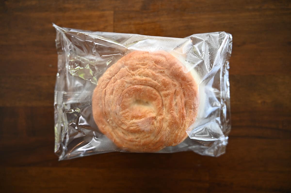 Top down image of one breakfast sandwich in it's individually wrapped plastic package sitting on a table.