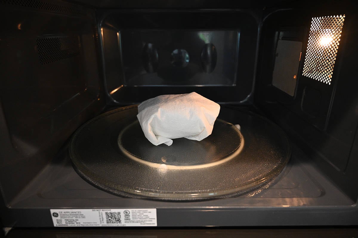 Image of a Kirkland Signature Breakfast Sandwich wrapped in paper towel being microwaved.
