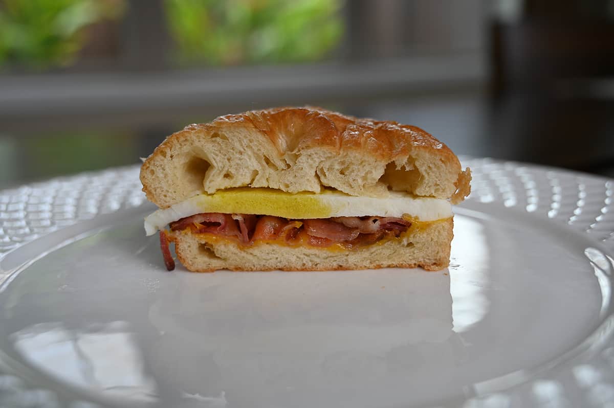 Closeup image of a breakfast sandwich cut in half so you can see the middle of the sandwich and everything that's in it.