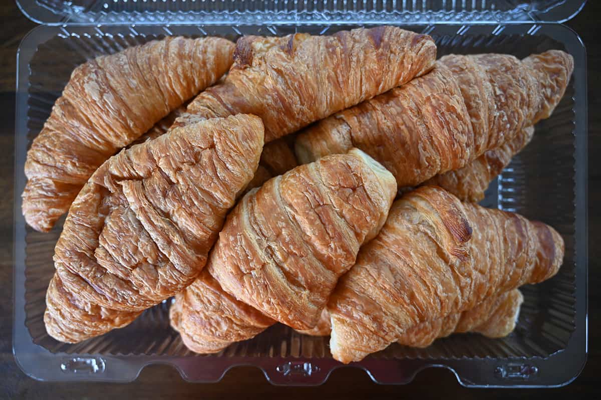 Top down image of an open container of croissants, sitting on a table.