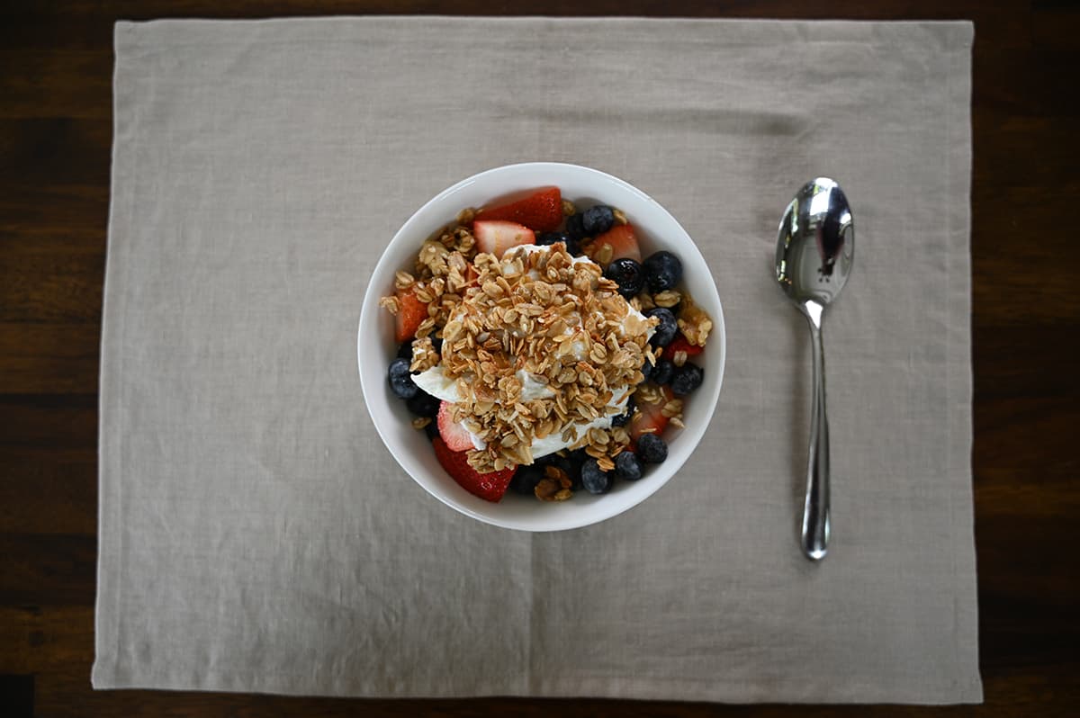 Top down image of a bowl of fruit with yogurt on top and granola on top of the yogurt.