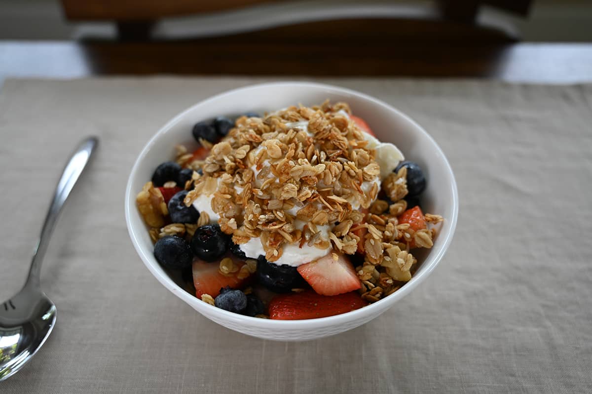 Side view close up image of a bowl with berries with white yogurt on top and granola on top of the yogurt.